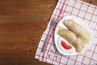 Cabbage rolls with beef, rice and vegetables on a linen tablecloth on a brown wooden background.