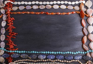 Frame of semiprecious stone beads on a black background, top view