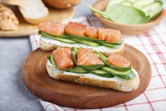 Smoked salmon sandwiches with cucumber and spinach on wooden board on a linen background. side