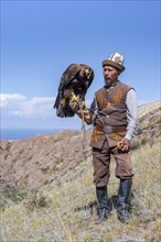 Traditional Kyrgyz eagle hunter with eagle in the mountains, near Kysyl-Suu, Kyrgyzstan, Asia