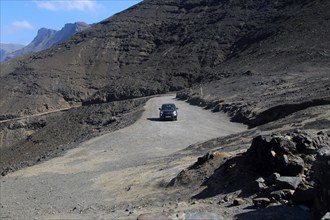 Car driving on unsurfaced road, Atlantic Ocean coast, Jandia peninsula, Fuerteventura, Canary