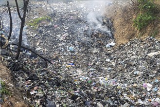 Coking rubbish dump, rubbish pit with waste and plastic rubbish, karst landscape near Vang Vieng,