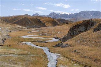 River Kol Suu winds through a mountain valley with hills of yellow grass, Naryn Province,