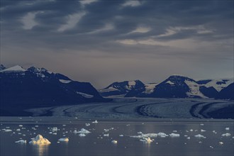 Evening mood with clouds over a glacier, glacier tongue, fjord with icebergs in front of mountains,