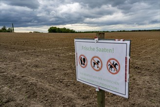 Sign on a field where crops have just been sown, with the request not to enter the field because of