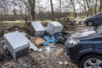 Illegal waste disposal in a car park, in a wooded area, tyres, furniture, refrigerators, household