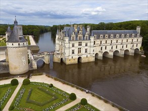 Renaissance castle on a bridge over a river, surrounded by well-tended parks, aerial view,