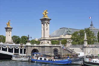 Boats on the river along the monumental bridge with golden sculptures, Paris