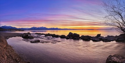 Twilight light over a calm lake with mountains and dramatic sky in warm colours, Chiemsee