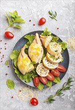 Stuffed baked squid with greens on a blue ceramic plate on a gray concrete background, top view,