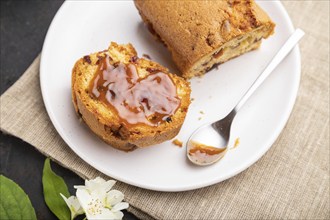 Homemade cake with raisins, almonds, soft caramel and a cup of coffee on a black concrete