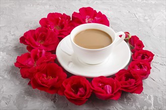 Red rose flowers in a spiral and a cup of coffee on a gray concrete background. Morninig, spring,