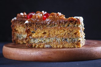 A piece of cake with caramel cream and poppy seeds on a wooden kitchen board. close up, selective