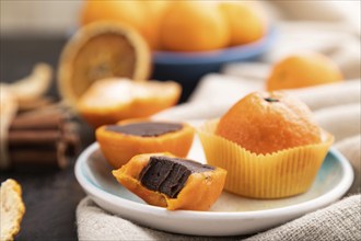 Truffle chocolate tangerine candies on a black concrete background and linen textile. Side view,