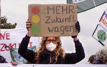 A demonstrator holds a sign with the Ampel logo and the words Mehr Zukunft wagen (Dare to have more