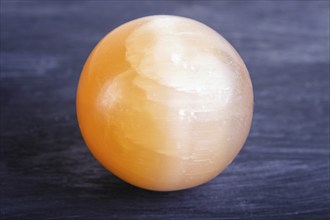 Orange onyx sphere on a black background, close up