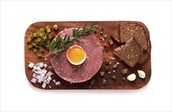 Beef tartare, with egg, capers, gherkins and bread, on a white background, top view, close up,