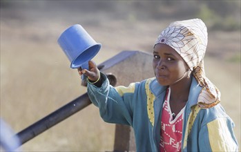 Young woman, girl drinking water from a plastic cup in Maraban Dare community in Plateau state,