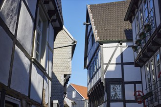 Tightly built and angled gables of half-timbered houses in grazing light against a blue sky in the