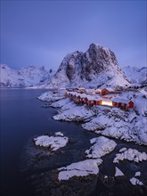 Rorbuer huts of Hamnoy at the fjord at dusk, snowy mountains in the background, Hamnøy, Reine,