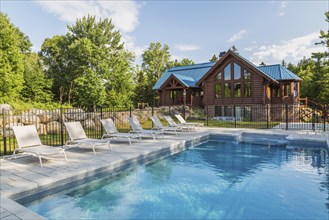 In-ground salt water swimming pool and brown stained milled Eastern white pine timber and flat log