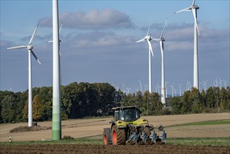 Farmer working in the fields, with a tractor, wind farm above the village of Lichtenau,