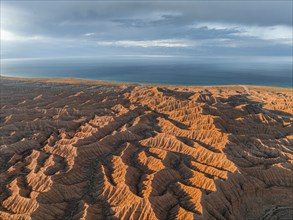 Landscape of eroded hills, badlands at sunset, Issyk Kul Lake in the background, aerial view,