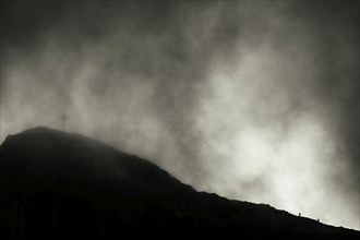 Summit of the Sulzfluh with ascending mountaineers and dramatic cloudy sky, Tschagguns, Rätikon,