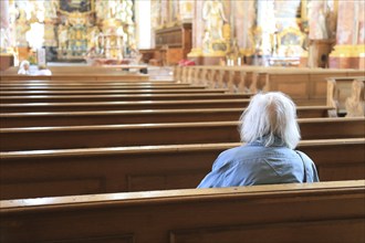 Old grey-haired woman as the only churchgoer, interior of the Cistercian Abbey Church Fürstenfeld