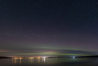 Northern lights (aurora borealis) shine on a starry night over Lake Plau, Ganzlin,