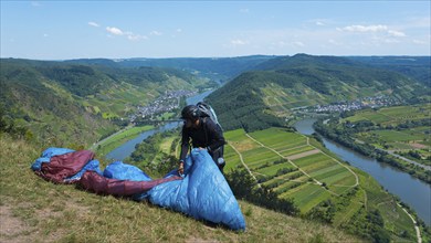 Paraglider prepares on the hill, with a wide view of the river and valleys, Paragliding, Bremm,