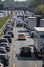 Emergency ambulance with flashing blue lights and siren working its way through a traffic jam on