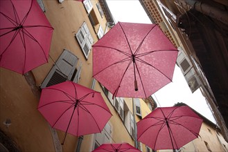 In the perfume town of Grasse, red umbrellas hang between the houses, Grasse, Provence-Alpes-Côte