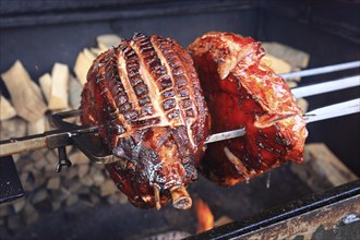 Pork knuckles are grilled on a spit over a wood fire