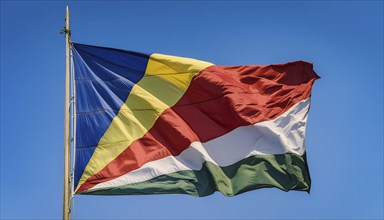 The flag of Seychelles, fluttering in the wind, isolated against a blue sky