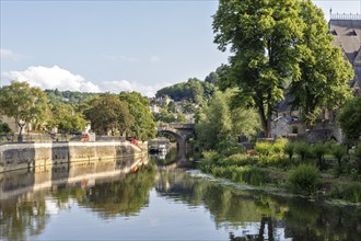 Tranquil river landscape with lush vegetation and bridge, Bath