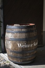 Old wine barrel on a house wall with the inscription Weinverkauf as a decorative advertising