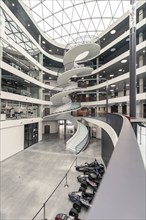 A modern, bright interior with a large spiral staircase, glass ceiling and industrial aesthetics,