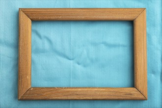 Wooden frame on smooth cotton blue tissue. Top view, flat lay, natural textile background and