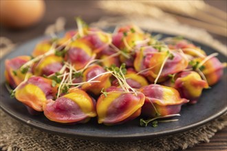 Rainbow colored dumplings with pepper, herbs, microgreen on brown wooden background and linen