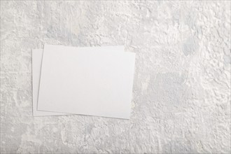 White paper business card, mockup on gray concrete background. Blank, flat lay, top view, still