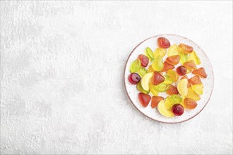 Various fruit jelly candies on plate on gray concrete background. top view, flat lay, copy space