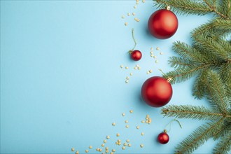 Christmas or New Year composition. Decorations, red balls, fir and spruce branches, on a blue paper