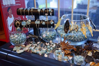 Various pieces of jewellery in aqua tones presented in glass jars on a sales table, sale of