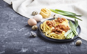 Tagliatelle bolognese pasta with minced meat on a black concrete background. side view, close up,