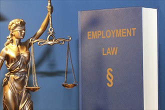 Symbolic image: Reference book Employment law (labour law) and a Justitia