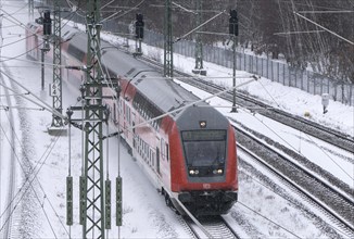 A Deutsche Bahn regional train runs over snow-covered railway tracks and stirs up snow, Berlin,