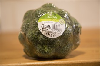 Broccoli head wrapped in plastic film with Tesco product label close up