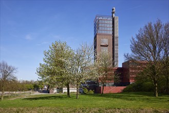 Tower of Nordstern colliery with statue of Hercules and delicately blossoming cherry tree (Prunus)