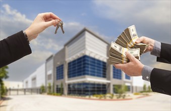 Man handing over thousands of dollars for the keys in front of new commecial building